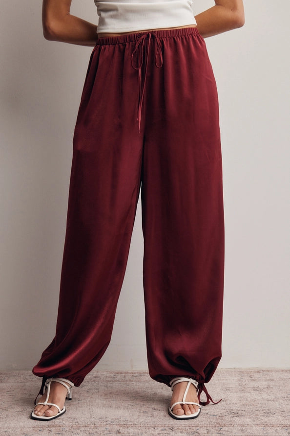Burgundy satin flowy pants with an adjustable ankle scrunch