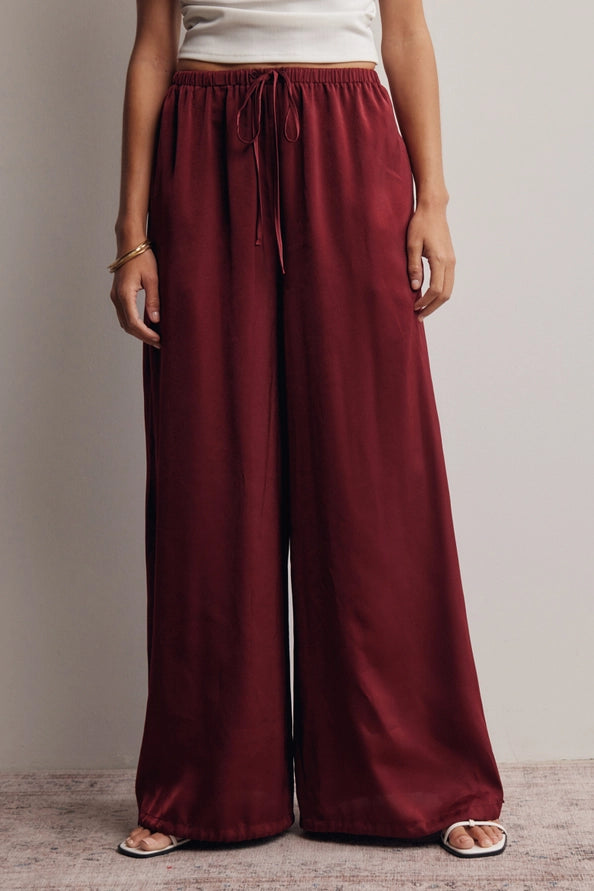 Burgundy satin flowy pants with an adjustable ankle scrunch